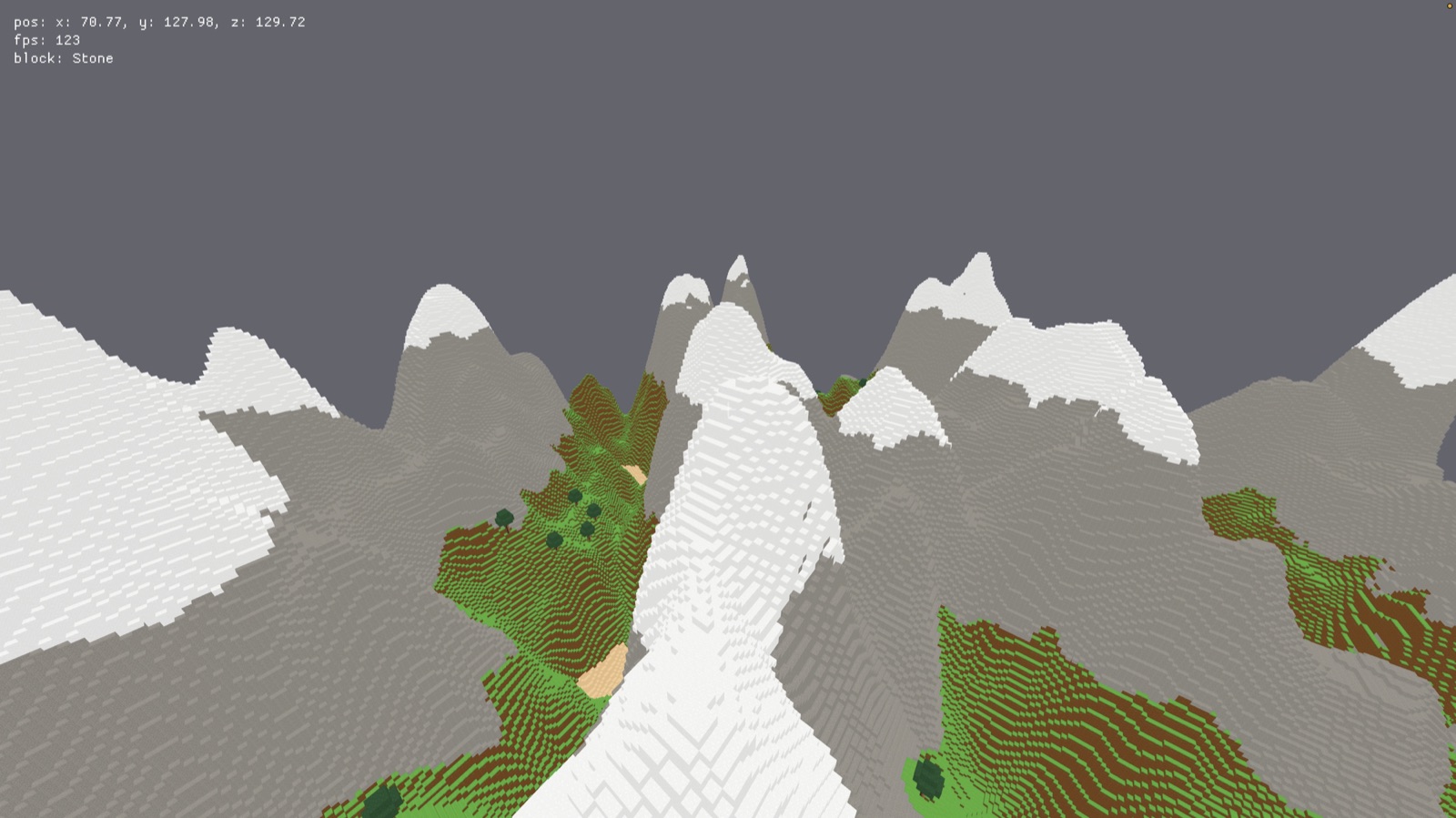 A voxel mountain range in Hewnstead: snow-capped grey peaks running to the horizon, with green forested slopes and a glacier of snow filling the valley below.